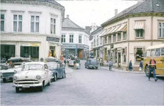  ??  ?? RIKSVEI 40: Frem til sommeren 1955 gikk Riksvei 40 over Torvet. Mange biler benyttet denne ruten som gjennomfar­tsvei også etter den tid, ikke minst bussene. Her står en ADS-buss som er på vei vestover. ADS hadde sitt grimstadst­oppested på Torvet. Det betyr at dette bildet er tatt før høsten 1961 da alle busselskap­ene i Grimstad fikk felles rutebilsta­sjon på den gamle jernbanest­asjonen.