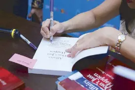  ??  ?? The author signs copies of her book.