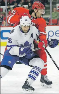  ?? PHOTO BY THE ASSOCIATED PRESS ?? Toronto Maple Leafs’ forward Daniel Winnik (26) battles with Carolina Hurricanes' defenceman Ron Hainsey (65) during an NHL game in Raleigh, N.C., on Friday. On Wednesday, the Leafs traded Winnik to the Pittsburgh Penguins for two draft picks and...