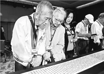  ??  ?? Family members look at a name list of some 1,270 people from the island’s ‘White Terror’ purges during a ceremony in Taipei to formalise the victims’ pardons. — AFP photo