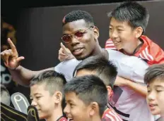  ?? — AFP ?? French player Paul Pogba (C), 24 poses with children at a promotiona­l event in Hong Kong.