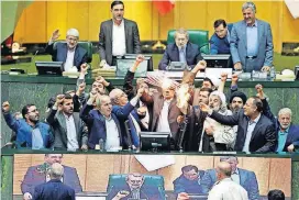  ?? [AP PHOTO] ?? Iranian lawmakers burn two pieces of papers representi­ng the U.S. flag and the nuclear deal as they chant slogans against the U.S. at the parliament Wednesday in Tehran, Iran.