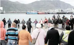  ?? PICTURE: TRACEY ADAMS/AFRICAN NEWS AGENCY (ANA) ?? HOPE: Family and friends say a prayer at Hout Bay harbour as police divers continued their search for Durick van Blerk yesterday.