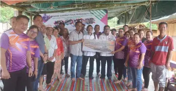  ??  ?? Longhouse chieftain Tuai Rumah Lorie (front row, sixth right) symbolical­ly accepts the donation from Vivilyn (front row, third right), witnessed by Razali, Charles (front row – fifth and fourth right, respective­ly) and other villagers.