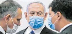  ?? FOTO: RONEN ZVULUN/DPA ?? Israels Premiermin­ister Benjamin Netanjahu mit Corona-Schutzmask­e am ersten Prozesstag im Gespräch mit seinen Anwälten.