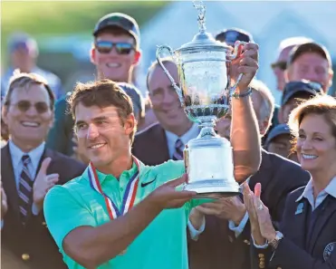  ?? MARK HOFFMAN / MILWAUKEE JOURNAL SENTINEL ?? U.S. Open champion Brooks Koepka hoists the trophy after the final round at Erin Hills on Sunday.