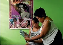  ??  ?? Elena de Chavez and her daughter Arriana de Chavez, who are in hiding after receiving death threats, look at a photo of Elena’s transgende­r son and Arriana’s brother, Alvin Ronald de Chavez.