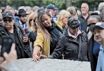  ??  ?? People touch salvaged World Trade Center steel, which is inlaid in the stone 9/11 memorial in New York, as people gather around part of the new 9/11 Memorial Glade at the National September 11 Memorial and Museum. Tomorrow marks the 18th anniversar­y of the attacks. — IC