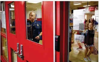  ?? JAMES GREGG / AMERICAN-STATESMAN ?? Dahlstrom Middle School seventh-grader Peyton Perry, 13, walks to class as school resource officer Deputy Manuel Moreno tends a security door between classes at the school in Buda. The Hays district spent $2M from a 2014 bond to reconfigur­e entrances...