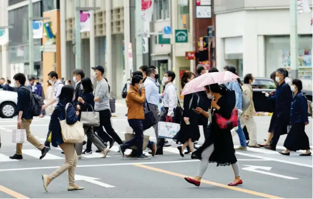  ?? Associated Press ?? ↑
People walk along a crossing in Tokyo on Wednesday.