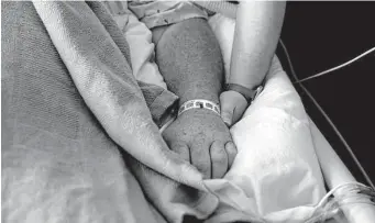  ?? Gerald Herbert/Associated Press ?? A woman, on oxygen as she recovers from COVID-19, holds the hand of her husband, who also has COVID-19, in Shreveport, La. A poll shows that adults find health care poorly handled.