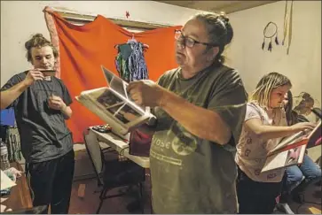  ?? Photograph­s by David Goldman Associated Press ?? BETTY OPPEGARD looks through memorabili­a with her grandchild­ren at her home on the White Earth reservatio­n in Minnesota. Her daughter, Beth Renee Hill, a mother of three, died of an overdose in 2020.