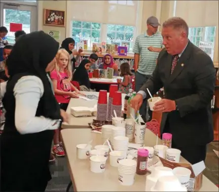  ?? PHOTOS PROVIDED ?? Assemblyma­n John McDonald III helps scoop ice cream to parents and kids during a recent visit at the Watervliet Public Library, where he visited to help promote summer youth reading.