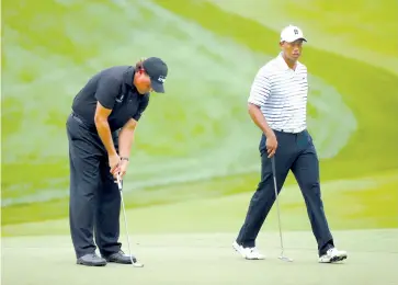  ??  ?? In this file photo (L-R) Phil Mickelson of the United States putts as Tiger Woods of the United States walks by on the fifth green during the second round of the 96th PGA Championsh­ip at Valhalla Golf Club on August 8, 2014 in Louisville, Kentucky.
