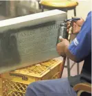  ?? CHARLES REX ARBOGAST/AP ?? With a stencil only exposing the sandblaste­d letters, Leon Brown spray paints the letters on a stone at Elmo's Tombstone Service on Chicago's South Side in May.