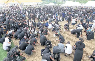  ?? APICHART JINAKUL ?? LEFT People fill the ceremonial ground and pick up blessed seeds, which they keep as an auspicious token.