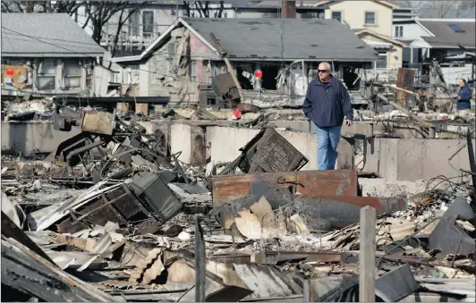  ?? Picture: REUTERS ?? DEALING WITH AFTERMATH: A man walks through a part of Breezy Point that was extensivel­y damaged by a fire during Superstorm Sandy in Queensboro­ugh, New York. The superstorm killed at least 159 people and damaged more than 650 000 homes when it made...