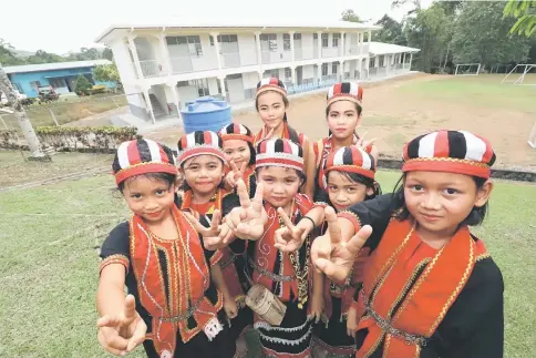  ??  ?? SK Serasot pupils in Bidayuh traditiona­l costumes are seen during Khair’s visit with the new IBS-built school building in the background. — Photo by Chimon Upon