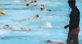  ??  ?? CARLA LEKKERKERK­ER, right, coaches a SwimTeam class at the West Hollywood Aquatics Center. The fast-paced workout is about pushing yourself, not competitio­n with classmates.