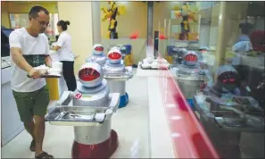  ?? ASIA NEWS PHOTO ?? Robots serving customers at a restaurant in Kunshan, Jiangsu province in 2014. Mainland authoritie­s have been investing massively in the robotics industry by offering subsidies to robotics companies. However, the incentives have also triggered chaos in...