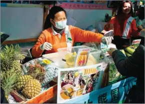  ?? ISAAC LAWRENCE/AFP ?? A stall owner wears a facemask as she sells produce at the farmers market in the Kowloon district of Hong Kong on January 13. Hong Kong’s famous skyline was engulfed in smog on January 22, with residents urged to stay indoors.