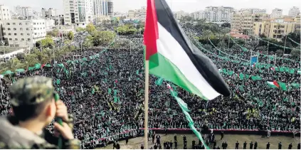  ?? PHOTO: REUTERS ?? Show of solidarity . . . A Palestinia­n flag is seen as Hamas supporters take part in a rally marking the 30th anniversar­y of Hamas’ founding, in Gaza City yesterday.