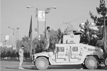  ??  ?? An Afghan security personnel keeps watch as he stands on an armoured humvee vehicle near the al-Zahra mosque in Kabul. — AFP photo