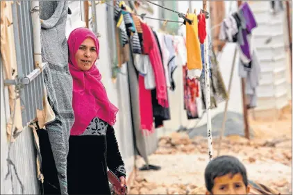  ?? AP PHOTO ?? Syrian refugees stand outside during a visit by UN refugee chief Filippo Grandi to the Zaatari Syrian Refugee Camp, in Mafraq, Jordan on Monday. Grandi said the number of Syrian refugees deported from Jordan to their war-ravaged homeland has “decreased...