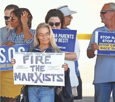  ?? PATRICK BREEN/THE REPUBLIC FILE ?? People hold signs during a protest against critical race theory at Coronado High School in Scottsdale in May. Conservati­ves have even been pushing to defund public schools over the topic, writes Elvia Díaz.