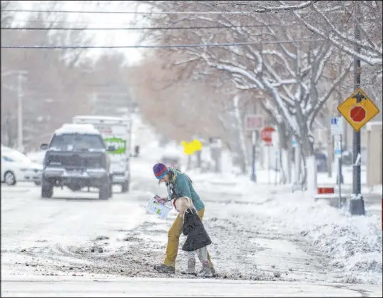  ?? Alex McIntyre The Associated Press ?? A woman and a child cope with a windy and snowy Saturday in Greeley, Colo., which canceled its Greeley Lights the Night parade.