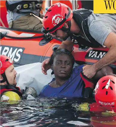  ?? PAU BARRENA / AFP / GETTY IMAGES ?? Members of the Spanish NGO Proactiva Open Arms rescue a woman in the Mediterran­ean Sea on Tuesday.