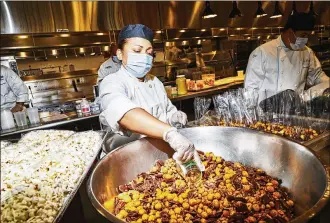  ?? AMY LOMBARD / THE NEW YORK TIMES ?? Chefs prepare boxed lunches at a kitchen run by Restaurant Associates, a major player in catering and corporate dining rooms, in Queens, N.Y. Offices are unlikely to be as full after the pandemic as they were before. Service businesses and their employees will have to adapt.