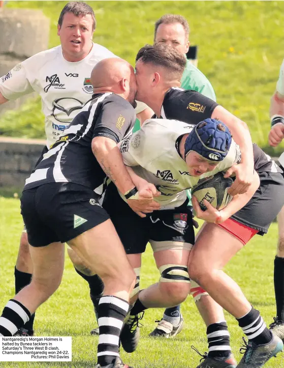  ??  ?? Nantgaredi­g’s Morgan Holmes is halted by Bynea tacklers in Saturday’s Three West B clash. Champions Nantgaredi­g won 24-22.
Pictures: Phil Davies