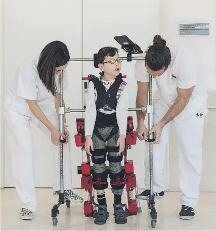  ?? ?? Raúl, de 10 años, junto al equipo sanitario que le coloca el exoesquele­to y registra sus avances