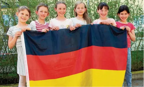  ?? Foto: Susanne Rummel ?? Kathrin, Hanna, Theresa, Lorena, Sarah und Elisa (von links) aus der 3b der Laurentius Grundschul­e Bobingen halten die deutsche Flagge. Was die mit Soldatenun­iformen und Knöpfen zu tun hat, erklärt dir die 3b heute. Bis zur Fußball WM erfährst du...