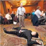  ?? MICHAEL ZAMORA/THE DES MOINES REGISTER ?? Actor Dylan Rohde stands over a victim at a performanc­e of The Dinner Detective in Des Moines, Iowa. The mystery dinner theater group specialize­s in corporate events.