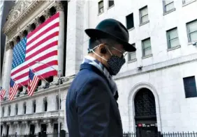  ?? AP FILE PHOTO/MARK LENNIHAN ?? A man passes the New York Stock Exchange in New York. Businesses are making more than enough extra income to cover the additional costs of inflation.