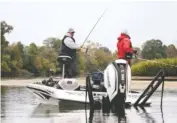  ??  ?? Dan Morehead, left, reels in a fish that was too small for him to keep during the Fishing League Worldwide Bass Fishing League Regional Championsh­ip tournament last month. Fish had to be at least 15 inches in length.