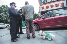  ?? PHOTOS BY CHEN ZHONGQIU / FOR CHINA DAILY ?? Left: Urban management officers explain the regulation­s to a man walking his dog on a street in Hangzhou. Right: A member of staff at a service center checks the details of a dog registered on Hangzhou’s digital informatio­n platform.