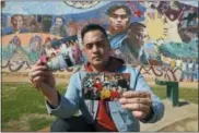  ?? REED SAXON — THE ASSOCIATED PRESS ?? In this Thursday photo, Filipino American Jeff DeGuia, 28, holds up family pictures at Unidad (Unity) Park in Los Angeles. DeGuia, 28, says it took his mother more than a decade to bring two sisters from the Philippine­s. “There’s definitely this idea...