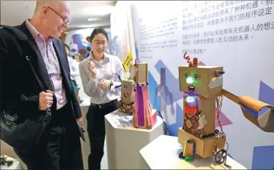  ?? ZHU XINGXIN / CHINA DAILY ?? A man looks at a robot during the World Economic Forum in Dalian, Liaoning province, on Wednesday.