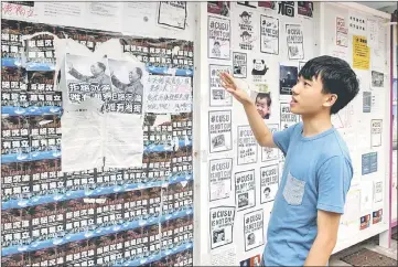  ??  ?? Au looks at the ‘democracy wall’ which has posters calling for and against semi-autonomous Hong Kong to split from the mainland, at the university campus in Hong Kong. — AFP photo