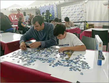  ?? JULIE JACOBS VIA AP ?? A.J. Jacobs and his son Zane, 13, are shown during an event at the 2019World Jigsaw Puzzle Championsh­ip in Spain. There were 40 countries represente­d at this competitio­n. Jigsaw puzzles are in vogue. There are puzzles left out in offices and at coffee shops, puzzle clubs and competitio­ns online, and artistic, mind-bending puzzles that sell for thousands of dollars.