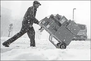  ?? AP/CHARLES KRUPA ?? packages across a snow-covered Boston street on Thursday. A foot of snow was forecast for the Boston area.