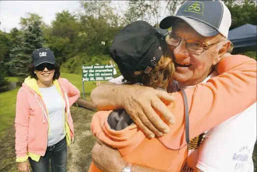  ?? Rebecca Droke/Post-Gazette ?? John Unger, right, one of nine miners rescued from the Quecreek Mine in 2002, receives a hug Saturday from Linda Buterbaugh, of Commodore, Pa., as her friend Rose Ann Buterbaugh looks on during the Quecreek Community Celebratio­n Day at the Quecreek Mine Rescue Site in Somerset County.