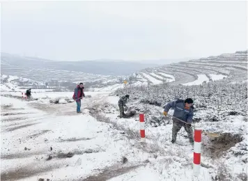  ?? KEITH BRADSHER/THE NEW YORK TIMES ?? Constructi­on workers shovel dirt onto a road for traction Dec. 16 near a remote mountain village that is part of China’s poverty alleviatio­n program in Gansu province.