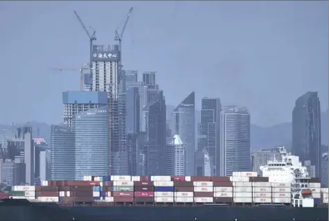  ?? Chinatopix via AP ?? A container ship sails past the city skyline of Qingdao in eastern China's Shandong province.