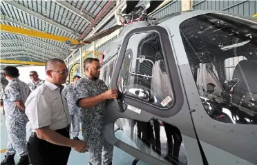  ?? — bernama ?? Valuable assets: admiral mohd reza (right) looking at the cockpit of the aw139 in Kota Kinabalu.