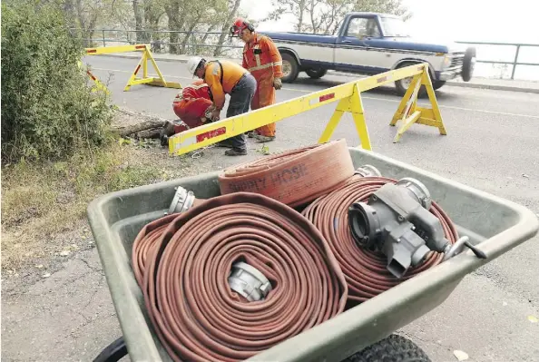  ?? GAVIN YOUNG ?? Workers set up hoses to draw water from Waterton Lake this week just ahead of Friday’s orders from Parks Canada officials to evacuate the town and provincial park as strong winds threaten to push a wildfire from British Columbia into the area.