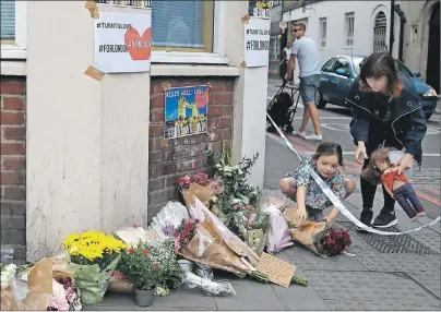  ?? AP PHOTO ?? A small child lays flowers at a corner tribute in the London Bridge area of London on Sunday. Police specialist­s collected evidence in the heart of London after a series of attacks described as terrorism killed several people and injured more than 40...